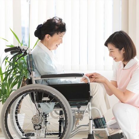 車いすの女性に寄り添う女性ヘルパー